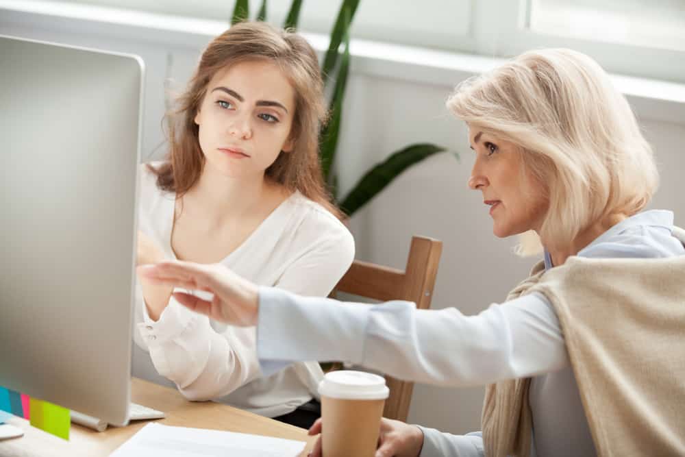 duas mulheres conversando sobre o que veem na tela de um computador